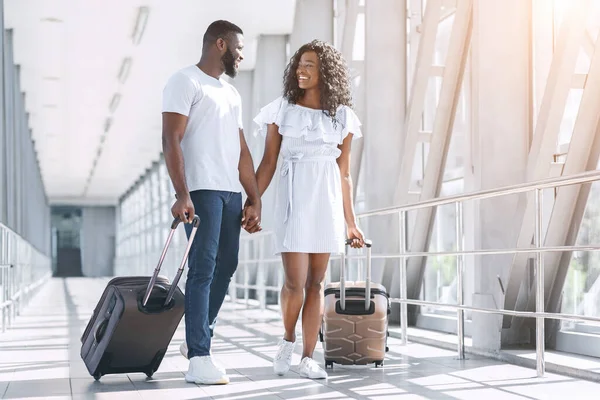 Casal negro afetuoso desfrutando de viagem de lua de mel, andando com malas em Aiport — Fotografia de Stock