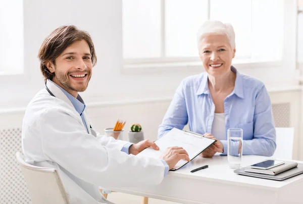 Alegre doctor hablando con paciente mayor en el consultorio — Foto de Stock