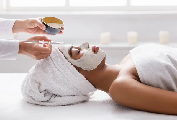 Joven mujer africana recibiendo tratamiento facial en el spa —  Fotos de Stock