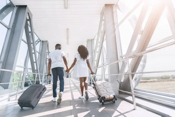 Visão traseira do casal afro andando com malas no terminal do aeroporto — Fotografia de Stock