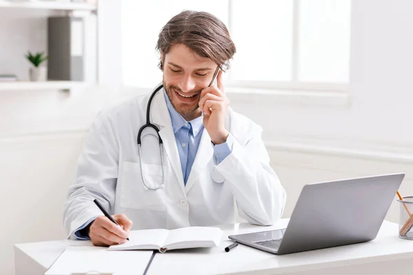 Doktor mluví s pacientem po telefonu a dělá si poznámky — Stock fotografie
