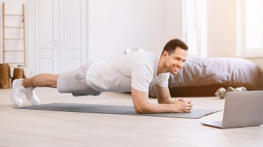 Mutlu adam evde, Panorama 'da dizüstü bilgisayarda kalas egzersizi yapıyor.