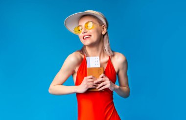 Uzun zamandır beklenen tatil seyahati. Mayo giymiş, elinde pasaportu olan genç bir kadın.