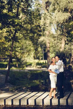 Yeni evli çift gülüyor ve eğleniyor. Park yerinde dikey duruyor.