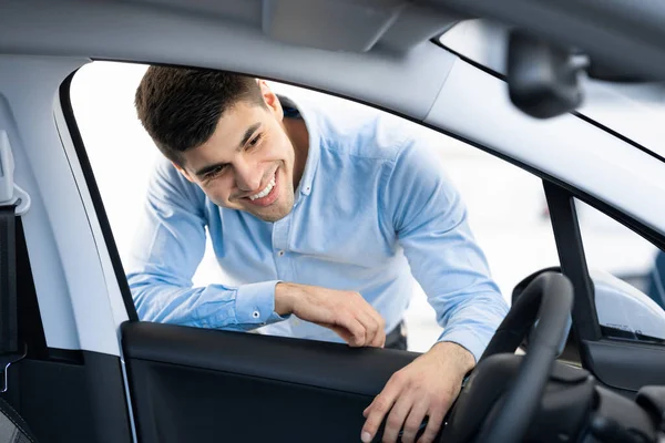 Bella sorridente ragazzo esaminando auto prima di acquistare — Foto Stock