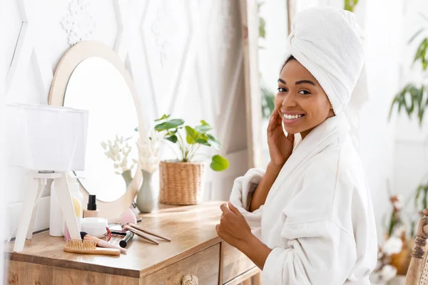 Femme noire assise à la table de toilette et touchant sa peau parfaite — Photo