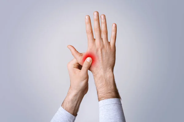 Inflamación en músculos y articulaciones. El hombre sostiene la mano roja resaltada — Foto de Stock