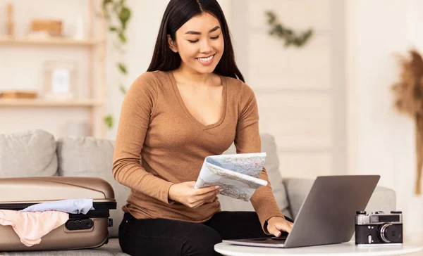 Glückliches chinesisches Mädchen sitzt am Laptop und hält Karte zu Hause — Stockfoto