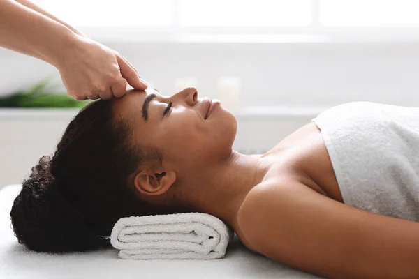 Avslappnad svart flicka liggande på spa, med huvud massage — Stockfoto