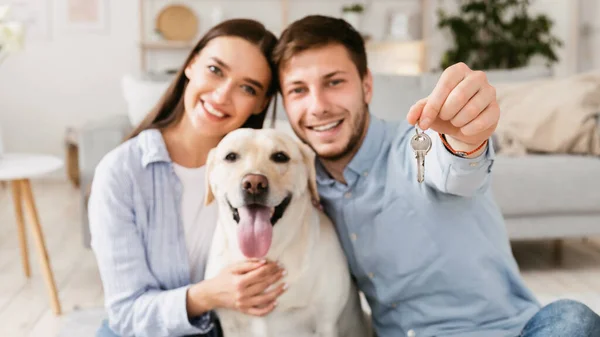 Joven feliz pareja con perro mostrando llaves —  Fotos de Stock