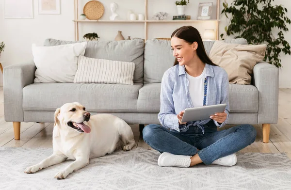 Jeune femme à la maison avec une tablette et un chien — Photo