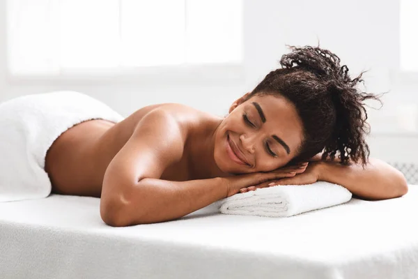 Fille africaine harmonieuse couchée au spa, attendant un thérapeute — Photo