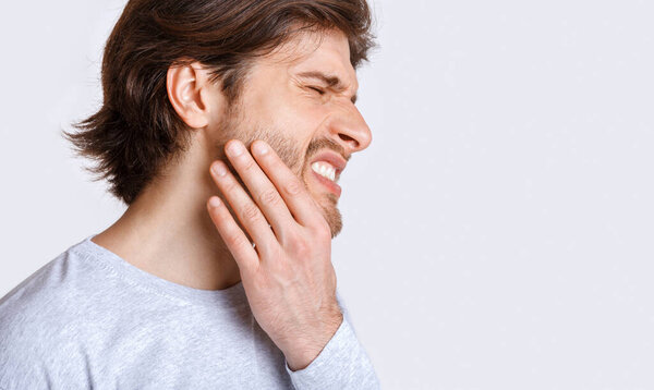 Not tolerate pain in teeth and dentures. Man suffers from pain and presses his hand to cheek