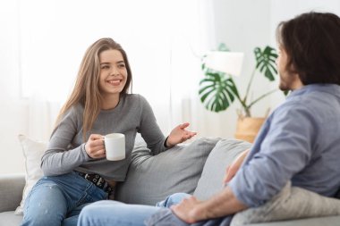 Neşeli kız kahve içiyor ve erkek arkadaşıyla konuşuyor.