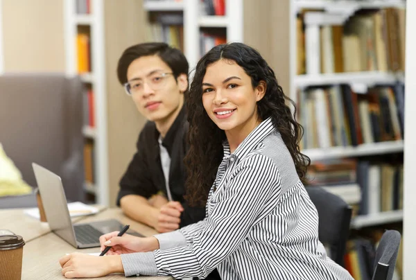 Sorrindo casal multicultural aprendendo na biblioteca do campus — Fotografia de Stock