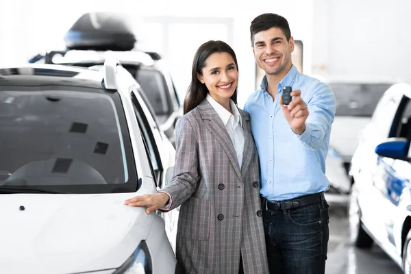 Cônjuges mostrando abraço chave do carro na loja de concessionárias — Fotografia de Stock