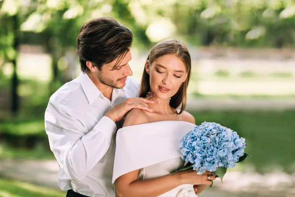 Groom Touching Brides Shoulder Hugging In Beautiful Nature Park — Stock Photo, Image