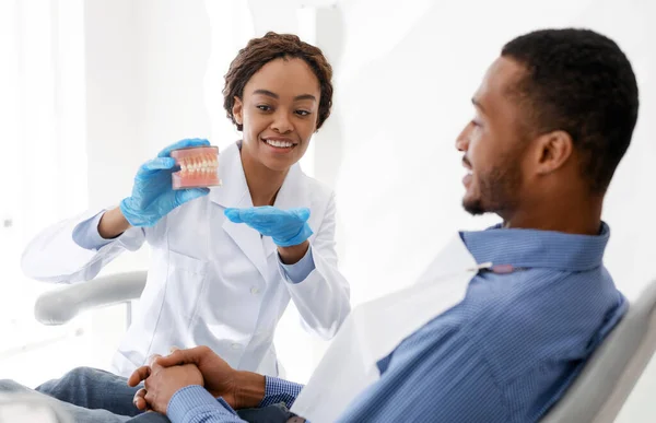 Dentista feminino mostrando modelo plástico paciente masculino de mandíbula humana — Fotografia de Stock