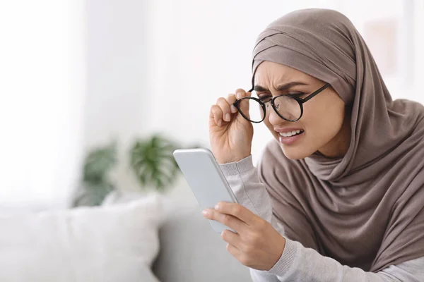 Povera vista. Donna musulmana in occhiali che tiene Smartphone, avendo problemi di visione — Foto Stock