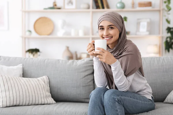 Home Tranquility. Portrait Of Relaxed Muslim Girl Sitting On Couch With Coffee — Stok Foto