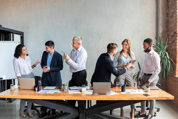 Colaboradores comunicando em pé durante reunião de negócios no escritório moderno — Fotografia de Stock