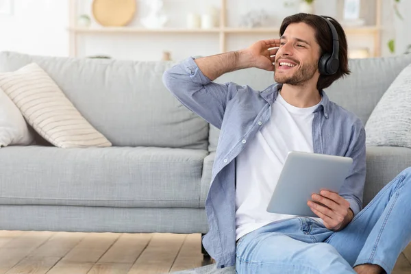 Hombre alegre escuchando música, sentado en el suelo en casa — Foto de Stock