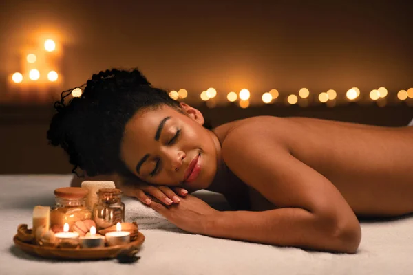 Joyful menina negra deitada na mesa de massagem no spa — Fotografia de Stock