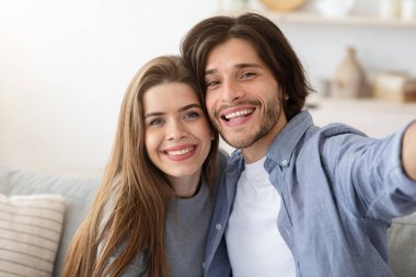 Aşık çift koltukta otururken selfie çekiyor.