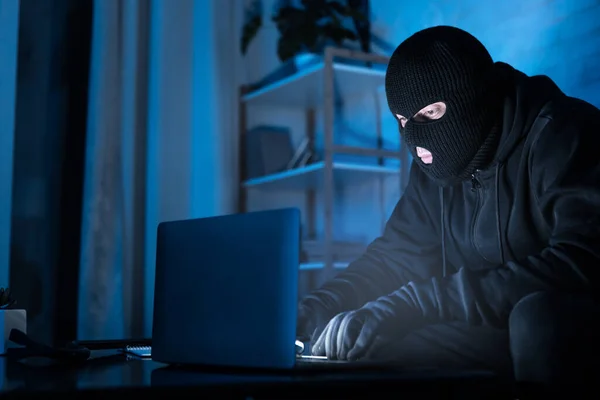 Хакер в маске скачивает частную информацию с помощью компьютера — стоковое фото