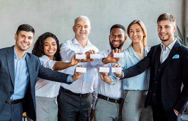 Gente de negocios alegre mostrando tarjetas de visita en blanco de pie en el interior — Foto de Stock