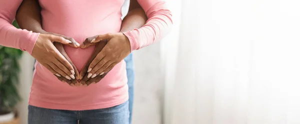 Mulher negra grávida segurando as mãos do marido em sua barriga, cortada — Fotografia de Stock