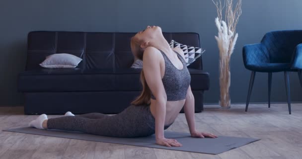 Chica delgada estirando la parte inferior de la espalda en la estera, la práctica de la pose cobra — Vídeos de Stock