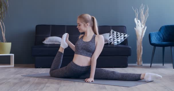 Sporty young woman making stretching legs exercise — Stock Video