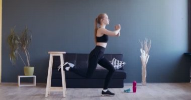 Genç kız çömeliyor, bir bacağını arkasında sandalyede tutuyor.