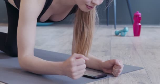 Junges Mädchen beim Planken und mit mobiler Anwendung — Stockvideo