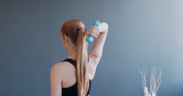 Achteraanzicht op meisjestraining met halters thuis — Stockvideo