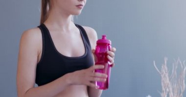 Kadın evde çalıştıktan sonra biberondan su içiyor.