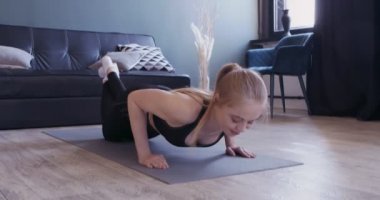Yoga minderinde dizlerinin üstünde şınav çeken güçlü bir kız.