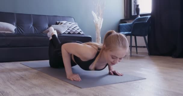 Сильная девушка делает интенсивные отжимания на коврике для йоги на коленях — стоковое видео