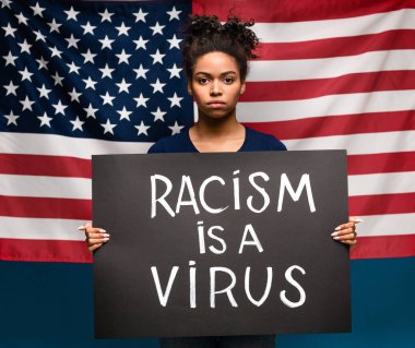 Amerikan bayrağı geçmişi olan, grev pankartı tutan Afrikalı Amerikalı bir kadın.