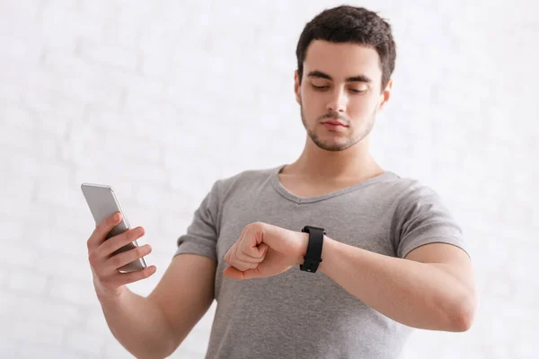 Moderne Technologien für den Sport. Kerl mit Fitness-Tracker auf der Hand und Smartphone, überprüft Aktivität — Stockfoto