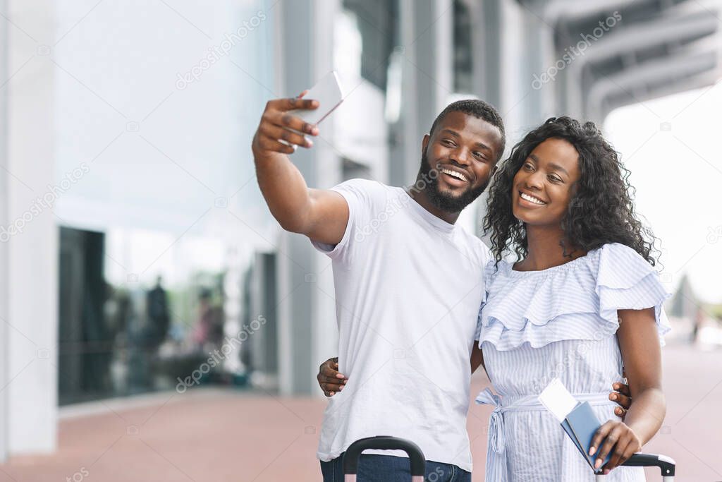 Honeymoon Memories. Happy romantic black couple taking selfie near airport terminal