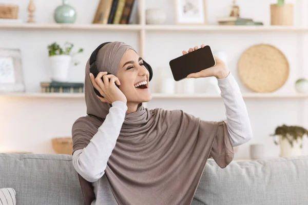 Kenyamanan yang menyenangkan. Wanita Arab ceria Mendengarkan Musik Di Rumah Dan Menyanyi — Stok Foto