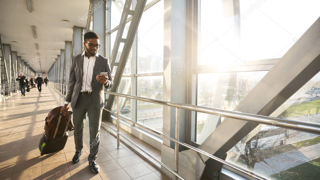 African Businessman Texting On Cellphone Walking In Airport Indoor, Panorama