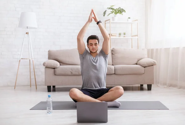 Trening online z gadżetami. Facet ze smartwatchem uprawia jogę, ogląda filmy treningowe w domu — Zdjęcie stockowe