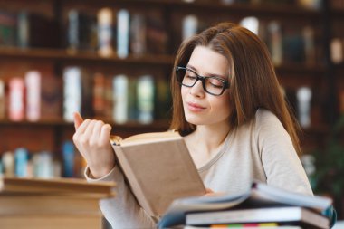 Gözlüklü düşünceli yetişkin öğrenci kitap okuyor.