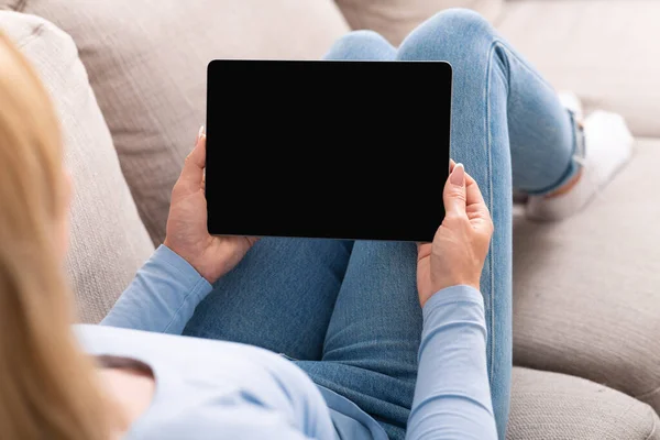 Onderwijs op de bank. Vrouw kijkt videoles op tablet met leeg scherm — Stockfoto