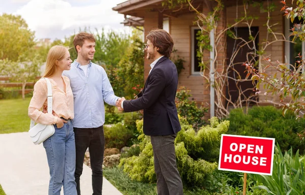 New home owners shaking hands with real estate agent near residential building outside, copy space — Stock Photo, Image