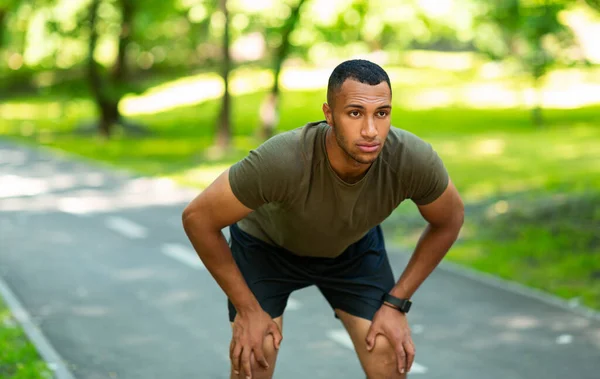 Guapo negro en ropa deportiva descansando después de su carrera matutina en el parque —  Fotos de Stock