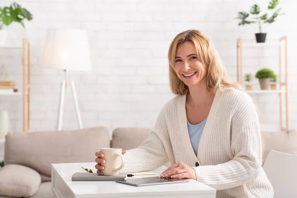 Une femme d'affaires travaille à la maison. Femme avec tasse, bloc-notes et tablette — Photo